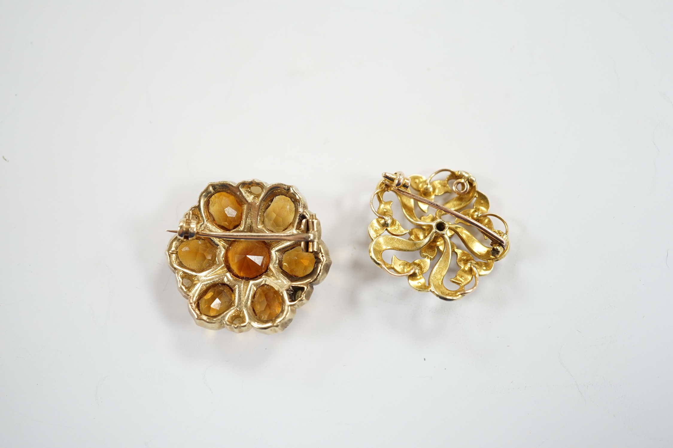 An early 20th century yellow metal, citrine and split pearl cluster set shaped circular brooch, 28mm and a similar 15ct and seed pearl cluster set brooch, gross weight 18.5 grams.